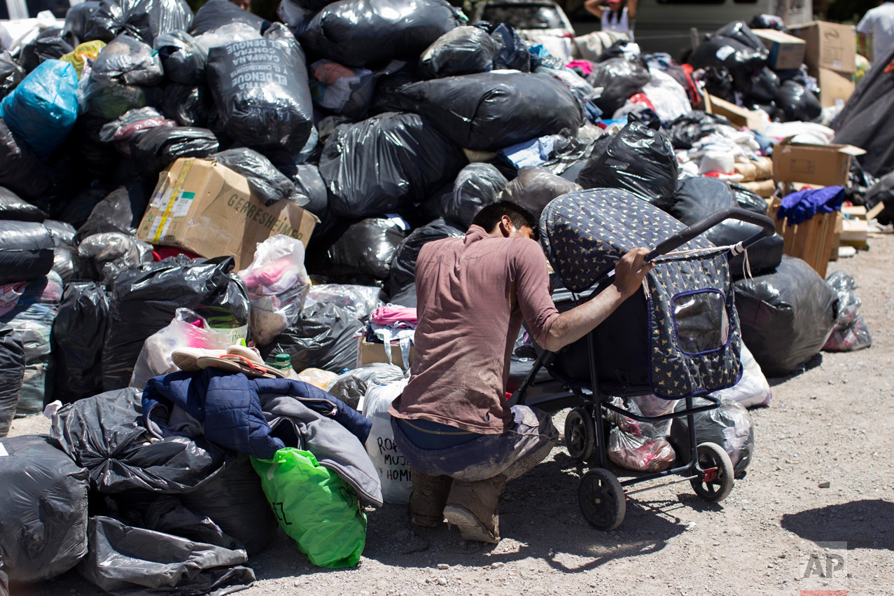 In this Jan. 13, 2017 photo, a resident looks at his son, next to a pile of bags full of donations in Volcan, Jujuy province, Argentina. The town was covered by a mudslide caused by the intense rains that hit the area one week ago, flooding it with mud, killing several and causing the evacuation of thousands. (Gianni Bulacio/Infoto via AP)