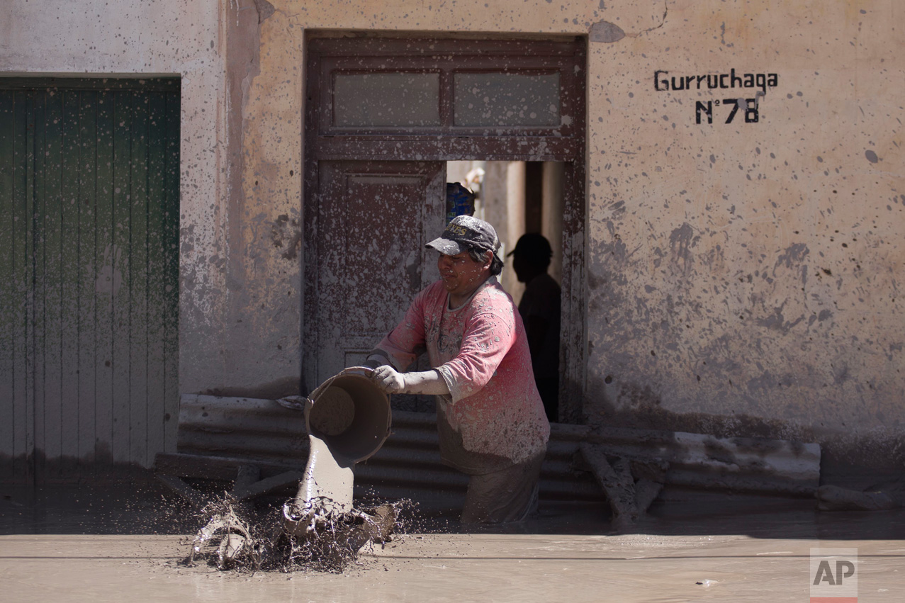 In this Jan. 13, 2017 photo, a resident begins the clean up of his mud flooded home in the town of Volcan, Jujuy province, Argentina. That town was covered by a mudslide a week ago after heavy rains hit the area. (Gianni Bulacio/Infoto via AP)