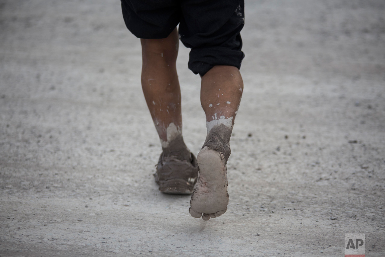 In this Jan. 13, 2017 photo, a man walks to a shelter in the mud stricken t town of Volcan, Jujuy province, Argentina. The mudslide was caused by the Intense rains that hit the area one week ago, flooding the town with mud, killing several and causing the evacuation of thousands. (Gianni Bulacio/Infoto via AP)
