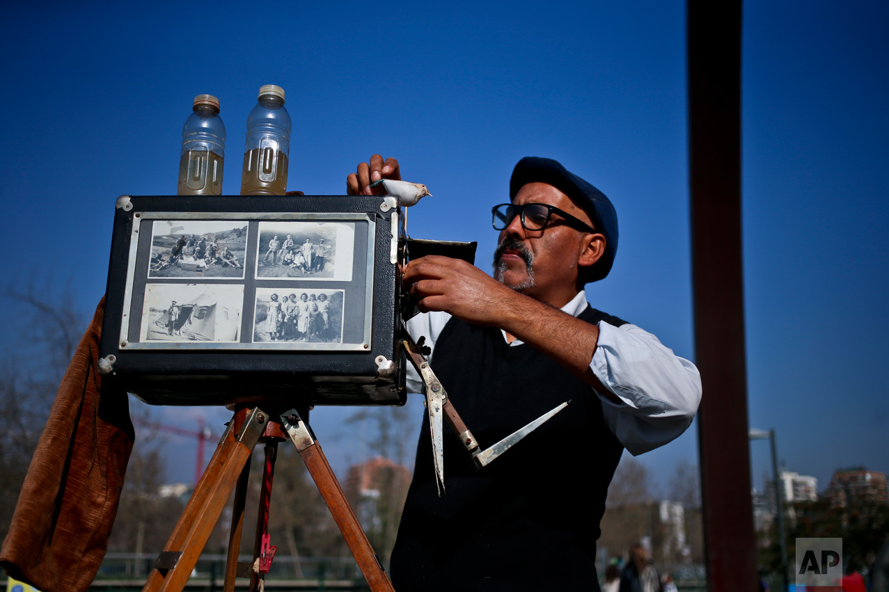 In this Sept. 2, 2016 photo, photographer Luis Maldonado prepares his old wooden box camera at a fair in Santiago, Chile. Maldonado is the last remaining photographer in the main square of the Chilean capital still using a wooden box camera. (AP Photo/Esteban Felix)