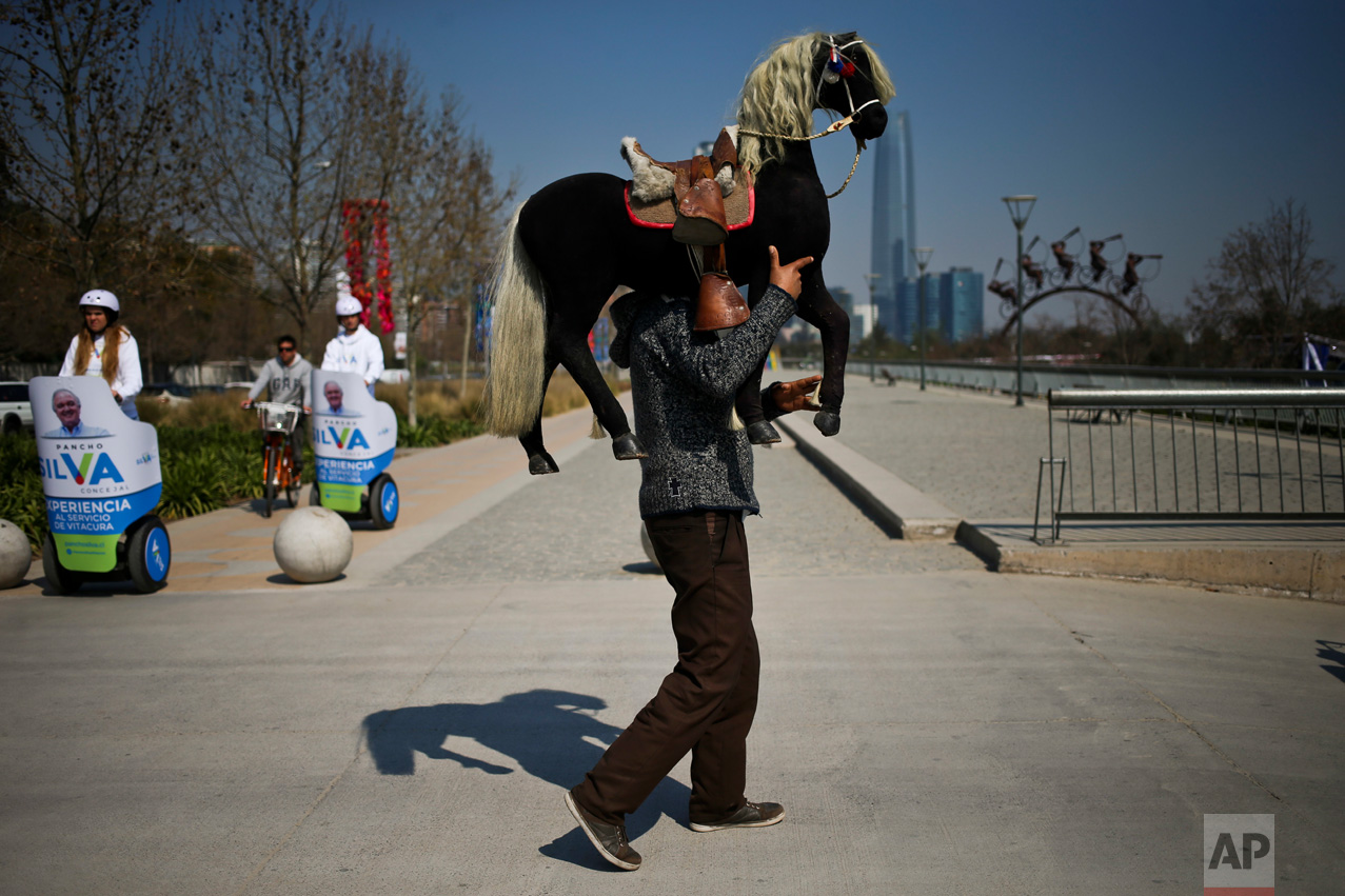 In this Sept. 2, 2016 photo, photographer Luis Maldonado carries a prop to a fair where he will set up his old wooden box camera and take clients' portraits in Santiago, Chile. "You need to live and also do the things you like in life," Maldonado said, smiling. "And I do what I like ... It's beautiful work, it's nostalgic and it's a part of me. I carry it in my veins." (AP Photo/Esteban Felix)