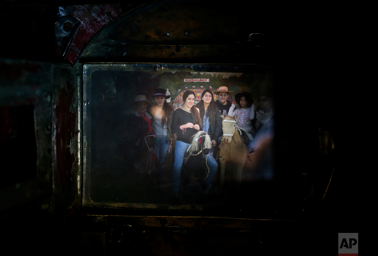 In this Sept. 4, 2016 photo, a family having their portrait taken fills the viewfinder of Luis Maldonado's old wooden old box camera, during a fair marking Independence Day in Santiago, Chile. The box camera's mechanism is simple: light enters through a lens and the photographic paper inside it captures a negative image of the subject photographed. (AP Photo/Esteban Felix)