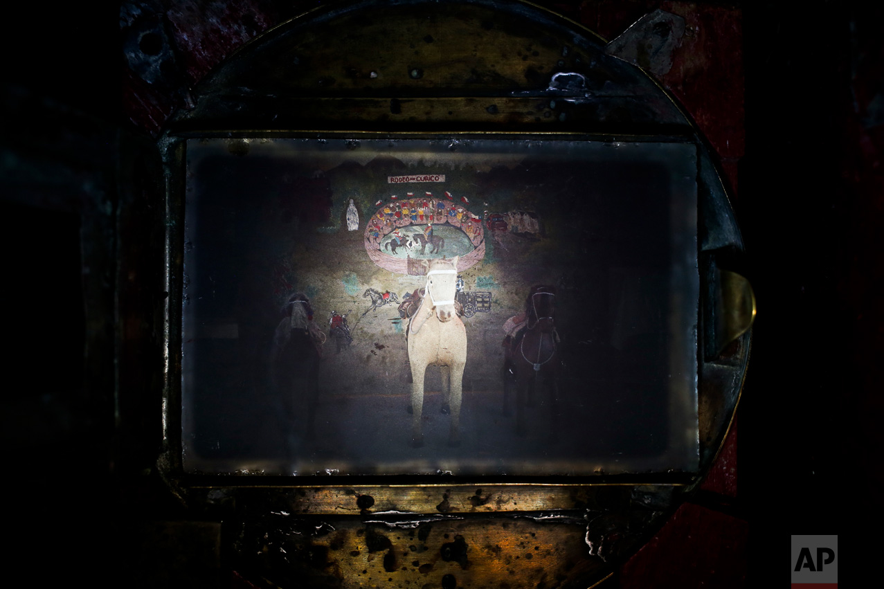 In this Sept. 2, 2016 photo, a prop horse for scenes set up by portrait photographer Luis Maldonado fills the viewfinder of his old wooden old box camera as he waits for clients during a fair celebrating Independence Day in Santiago, Chile. The box camera was developed and became popular in the late 19th century. (AP Photo/Esteban Felix)