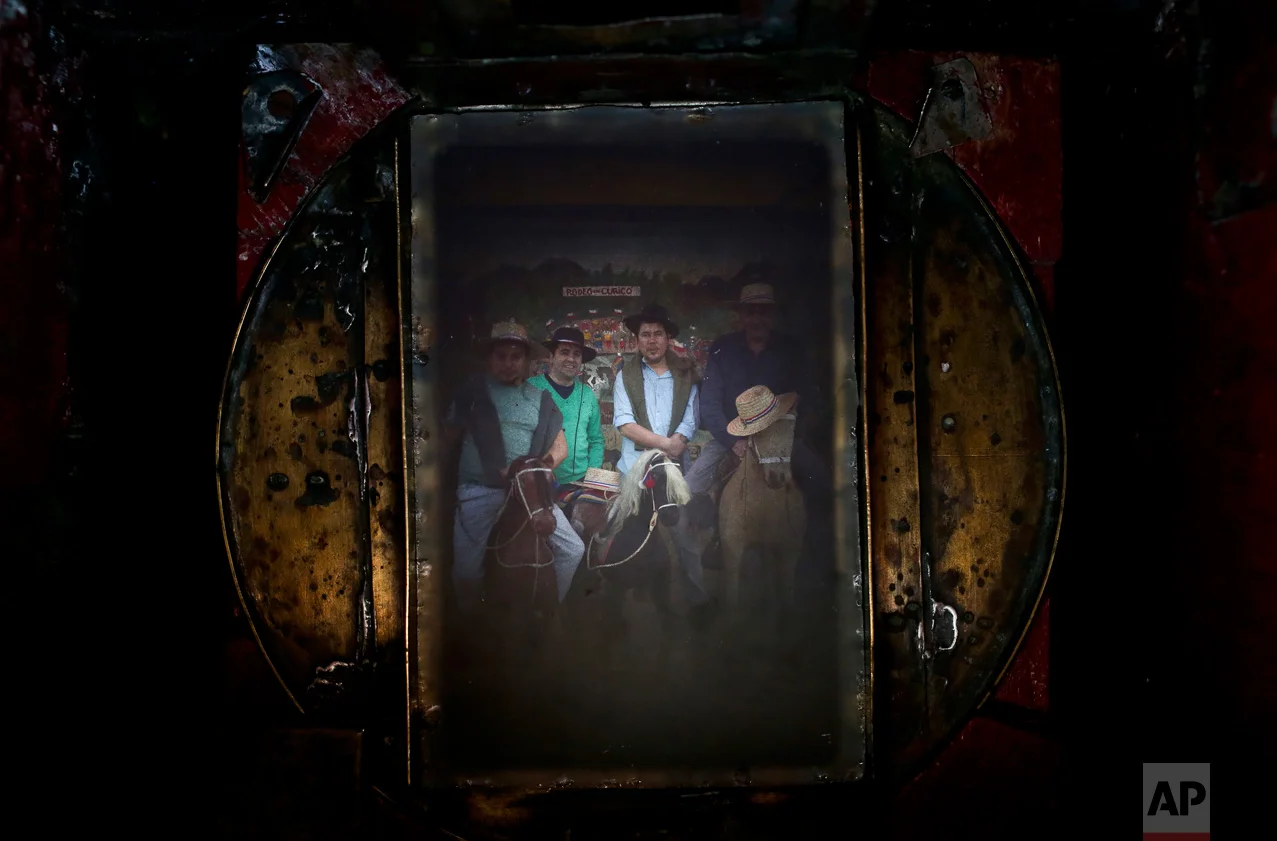 In this Sept. 4, 2016 photo, a group of friends fill the viewfinder of Luis Maldonado's old wooden old box camera, during a fair marking Independence Day in Santiago, Chile. The image making process lasts about 20 minutes, resulting in a vintage-looking image. (AP Photo/Esteban Felix)