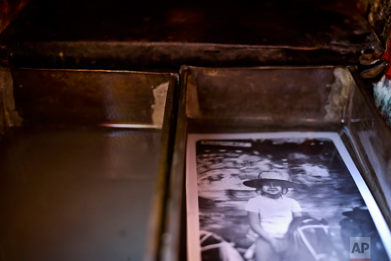 In this Sept. 4, 2016 photo, a portrait lays in fixer as it's developed inside Luis Maldonado's old wooden box camera in Santiago, Chile. The box works both as a camera and a photo lab. (AP Photo/Esteban Felix)