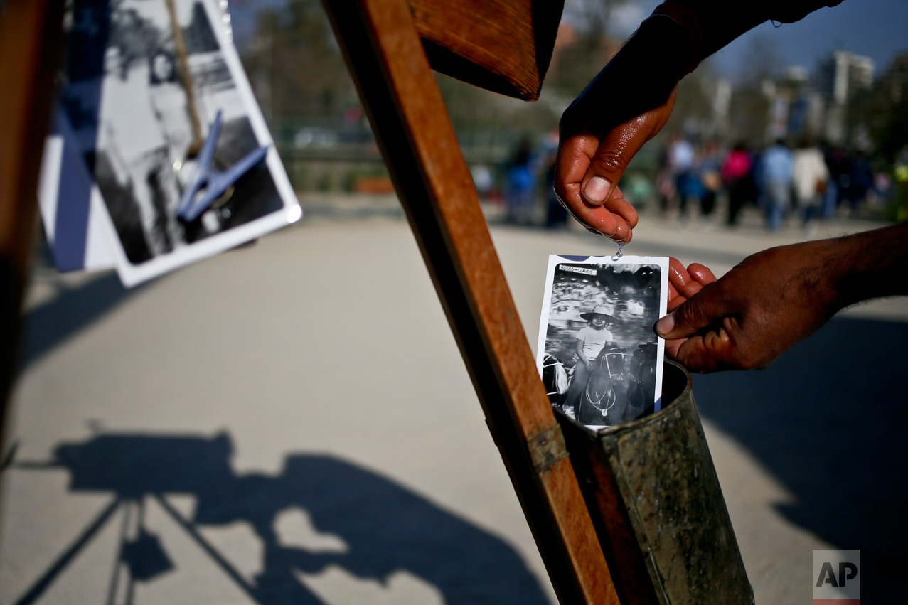 In this Sept. 4, 2016 photo, photographer Luis Maldonado rinses a freshly developed portrait taken with his old wooden box camera during a fair marking Independence Day in Santiago, Chile. "While I take one photo, my colleagues take 10," Maldonado said of other photographers who take digital photos at downtown Santiago's Plaza de Armas. (AP Photo/Esteban Felix)