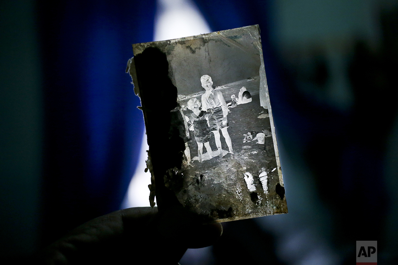 In this Dec. 20, 2016 photo, street photographer Luis Maldonado shows a negative that he says was made by his grandfather, his father, or his uncle, at his home in Santiago, Chile. Once the negative has been developed, the photographer takes a picture of the negative image, using his arm to hold a special paper in front of the lens to get a positive print. (AP Photo/Esteban Felix)