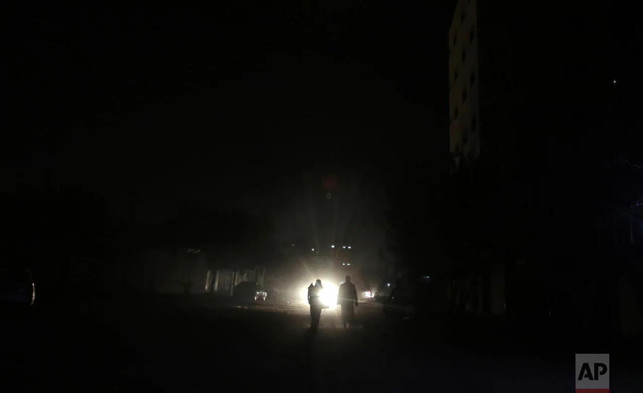 In this Monday, Jan. 16, 2017 photo, Palestinians walk on a dark street during the power cut in Gaza City. At night, large swaths of the Gaza Strip plunge into darkness - the result of chronic and worsening power outages. In crowded city streets, the only source of light comes from the headlights of passing cars. The power shortages are the worst to hit Gaza since Hamas seized control of the territory 10 years ago. (AP Photo/ Khalil Hamra)