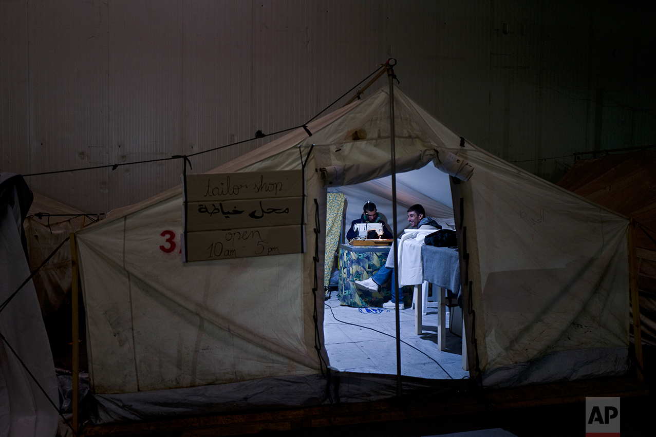 In this Wednesday, Jan. 18, 2017 photo, a Syrian refugee man repairs clothes at a tailor shop set up in a tent in Frakapor refugee camp on the outskirts of the northern Greek city of Thessaloniki. (AP Photo/Muhammed Muheisen)