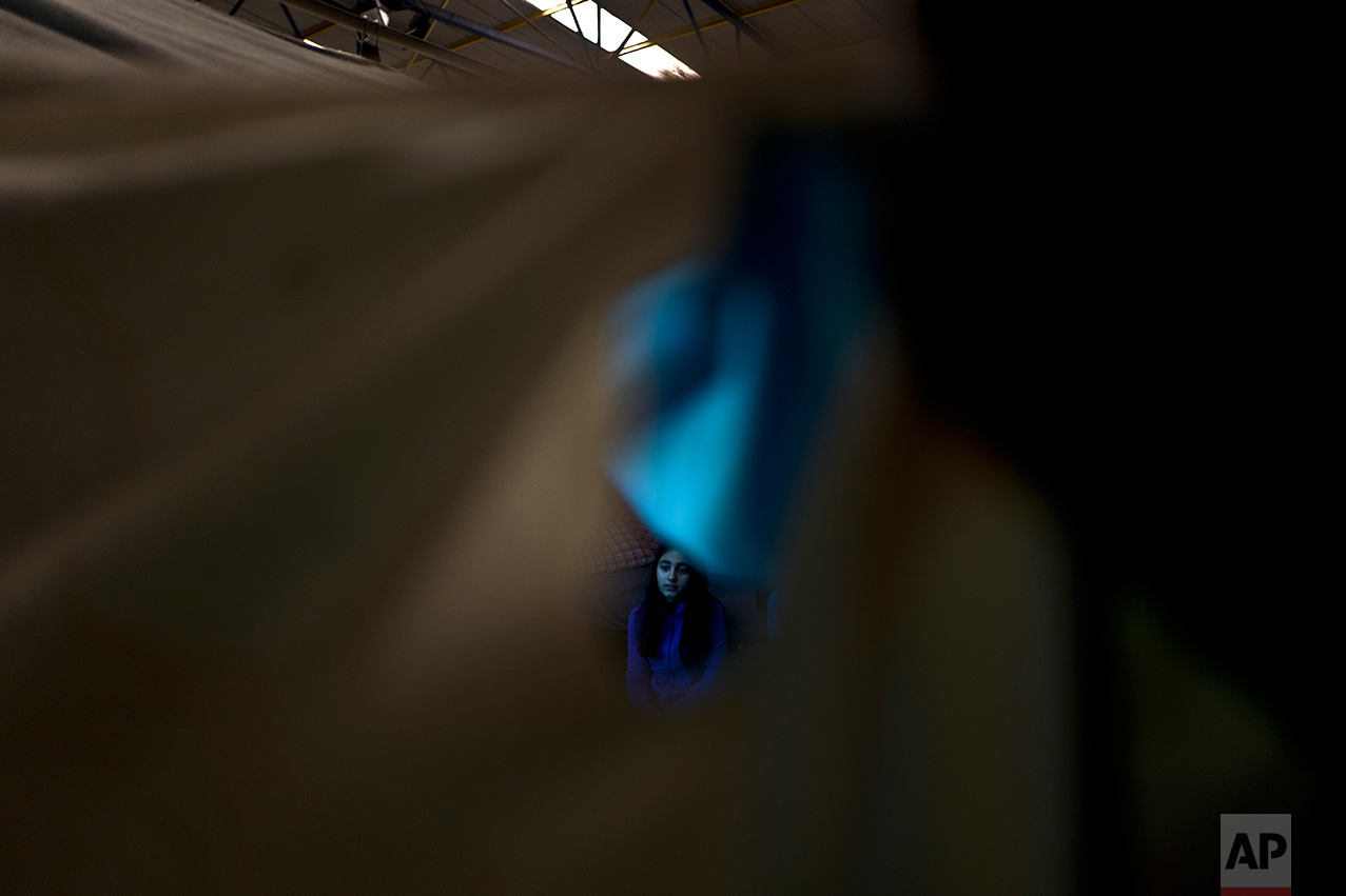 In this Wednesday, Jan. 18, 2017 photo, a Syrian refugee girl attends emotional support session provided to her and other refugees by volunteers from the Refugee Trauma Initiative, in a tent in Frakapor refugee camp on the outskirts of the northern Greek city of Thessaloniki. (AP Photo/Muhammed Muheisen)