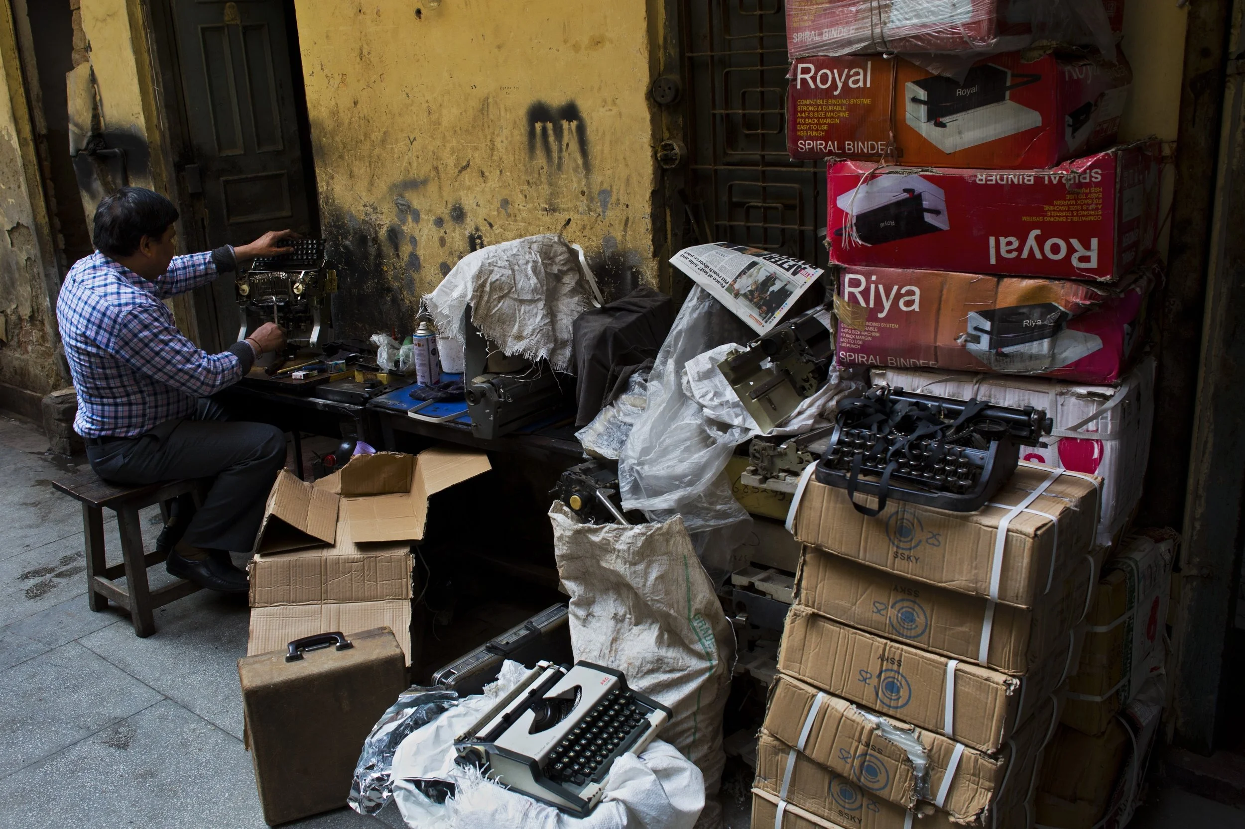 In this Jan. 18, 2017 photo, professional typists work on a roadside near Delhi's stock exchange market in New Delhi, India. India is one of the last places in the world where the typewriter continues to cling to life. This country has thousands of professional typists, most of them working outside the country's courts and government offices. But even in India, where stodgy government bureaucracies have helped the typewriter survive, its twilight is at hand. (AP Photo/Bernat Armangue)