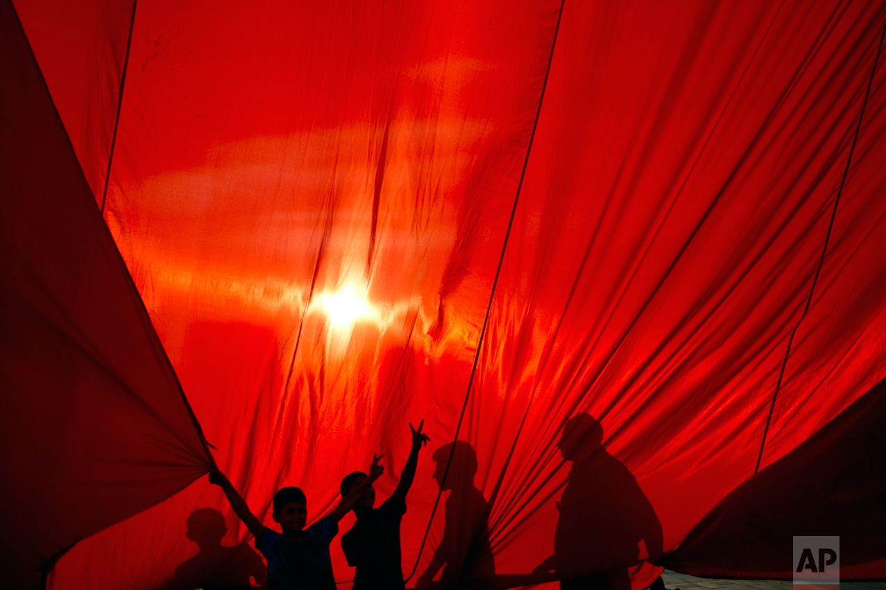 Protesters hold a giant Turkish flag as they gather in Taksim Square in Istanbul, Monday, July 18, 2016. Turkey's Interior Ministry has fired nearly 9,000 police officers, bureaucrats and others and detained thousands of suspected plotters following a foiled coup against the government, Turkey's state-run news agency reported Monday. (AP Photo/Petros Giannakouris)
