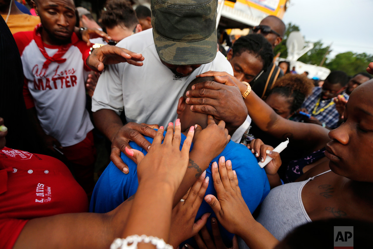 Cameron Sterling, son of Alton Sterling, is comforted by hands from the crowd at a vigil outside the Triple S convenience store in Baton Rouge, La., Wednesday, July 6, 2016. Alton Sterling, 37, was shot and killed by Baton Rouge police outside the store where he was selling CDs. (AP Photo/Gerald Herbert)