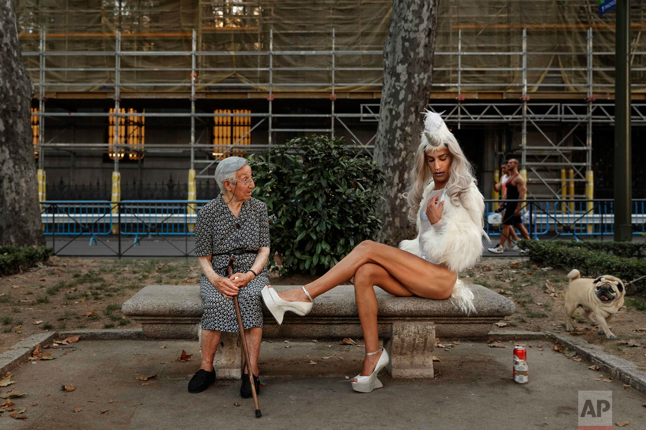 A woman looks across as a gay parade participant poses for pictures during Gay Pride parade in Madrid, Spain, Saturday, July 2, 2016. Hundreds of thousands of people defied high temperatures and relative security concerns and turned out in Madrid to march in Saturday's LGTB Pride parade, one of the biggest in Europe, along the streets of the Spanish capital, just three weeks after members of the gay, lesbian, bisexual and transgender community were tragically victimized in a shooting massacre at a United States nightclub. (AP Photo/Daniel Ochoa de Olza)