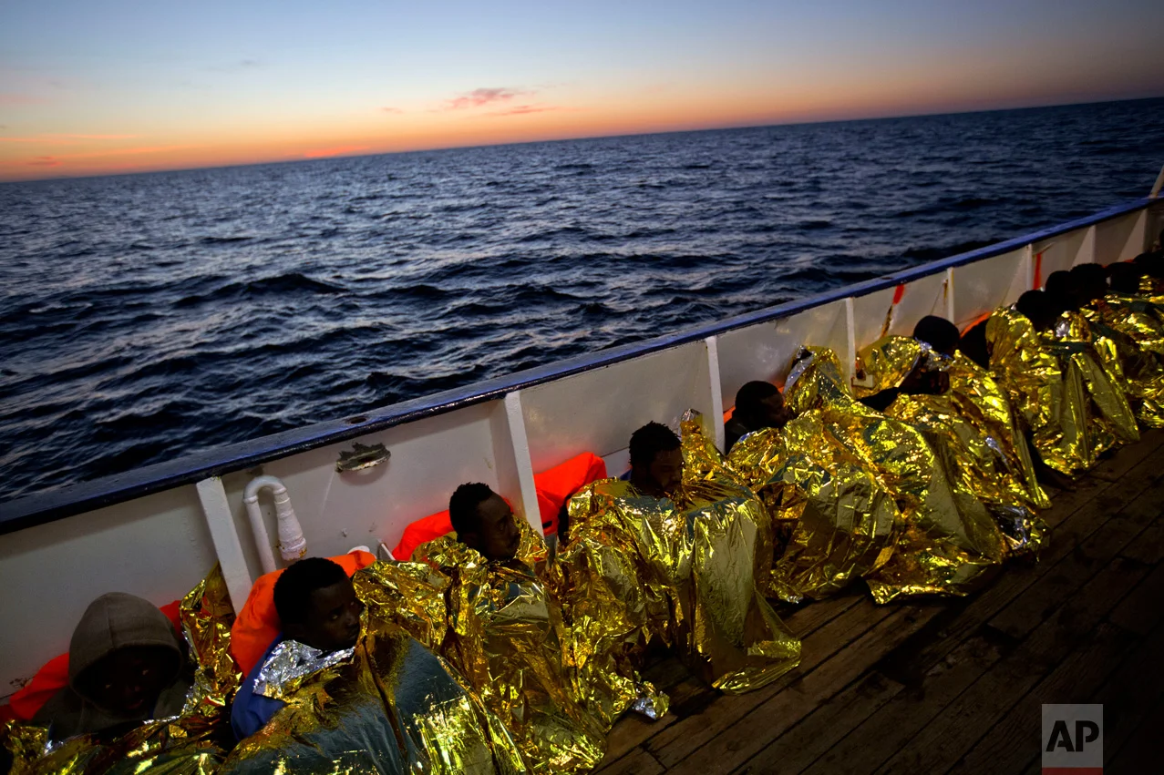 Wrapped in blankets, Sub-Saharan migrants sit on the deck of the ship Golfo Azzurro after their rescue from a rubber boat by members of the Proactive Open Arms organization in the Mediterranean sea, about 24 miles north of Sabratha, Libya, on Friday, Jan. 27, 2017. Tens of thousands of people seeking better lives are expected to trek across deserts and aboard unseaworthy boats from war-torn Libya this year in a desperate effort to reach European shores by way of Italy. (AP Photo/Emilio Morenatti)