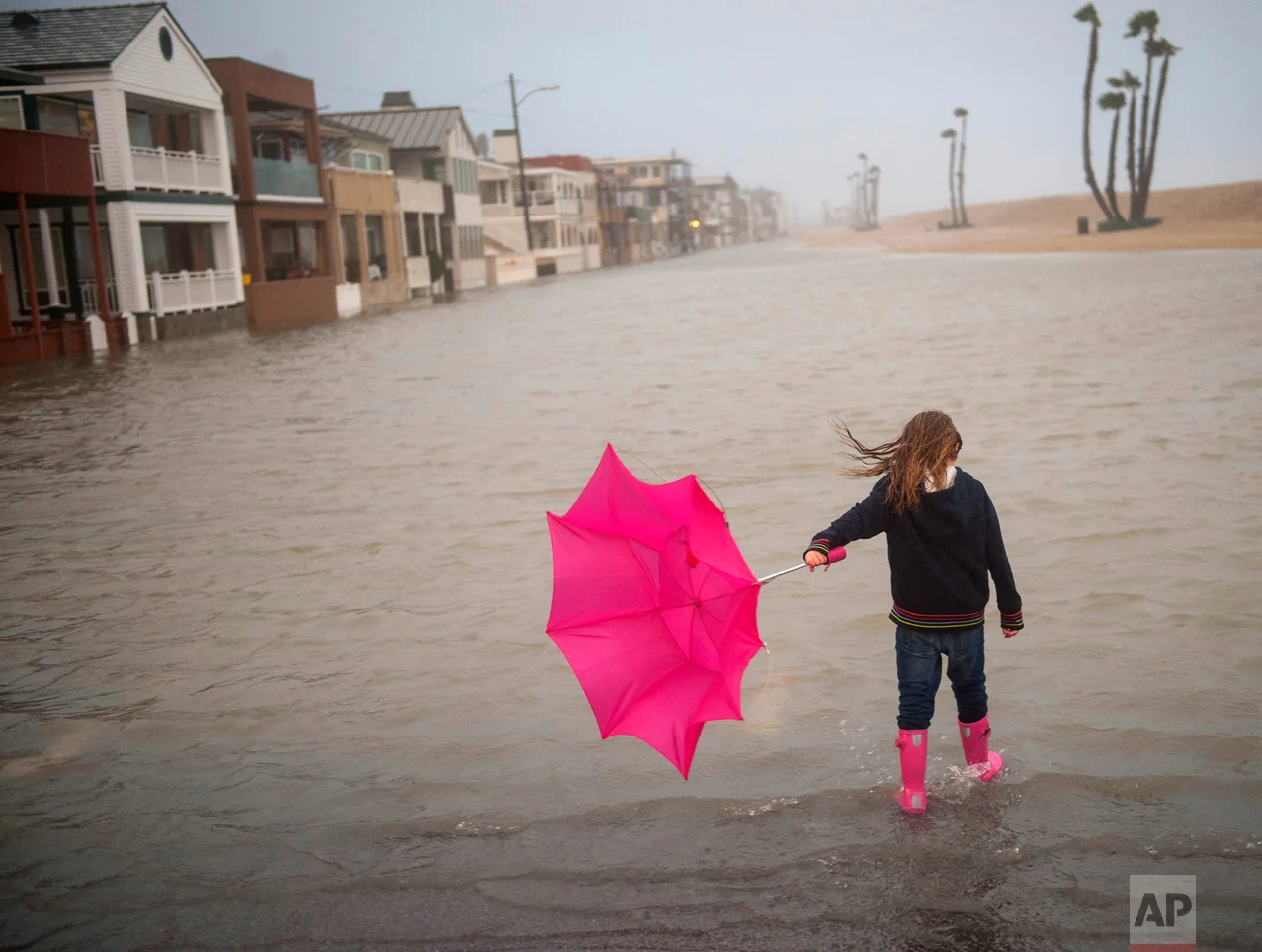 Isabella Busse, 6, holds an umbrella as she walks through floodwaters near the a pier during a storm in Seal Beach, Calif., Sunday, Jan. 22, 2017. The heavy downpour on Sunday drenched Orange County in one of the heaviest storms of the year. (Ana Venegas/The Orange County Register via AP)
