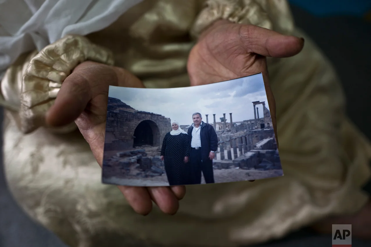 In this Saturday, Jan. 7, 2017 photo, Amineh Hamad, 58, a Syrian refugee from Eastern Ghouta near Damascus, shows a photograph of herself and her husband Ali Abdulqader, 58, at her shelter in the Ritsona refugee camp, Greece. "It was the last time we visited the Roman site of Busra al-Sham, a sunny Friday during the summer of 2010, we had a barbecue, walked and laughed a lot, a day from life, we miss these days, we hope one day it will come back." Amineh said. (AP Photo/Muhammed Muheisen)