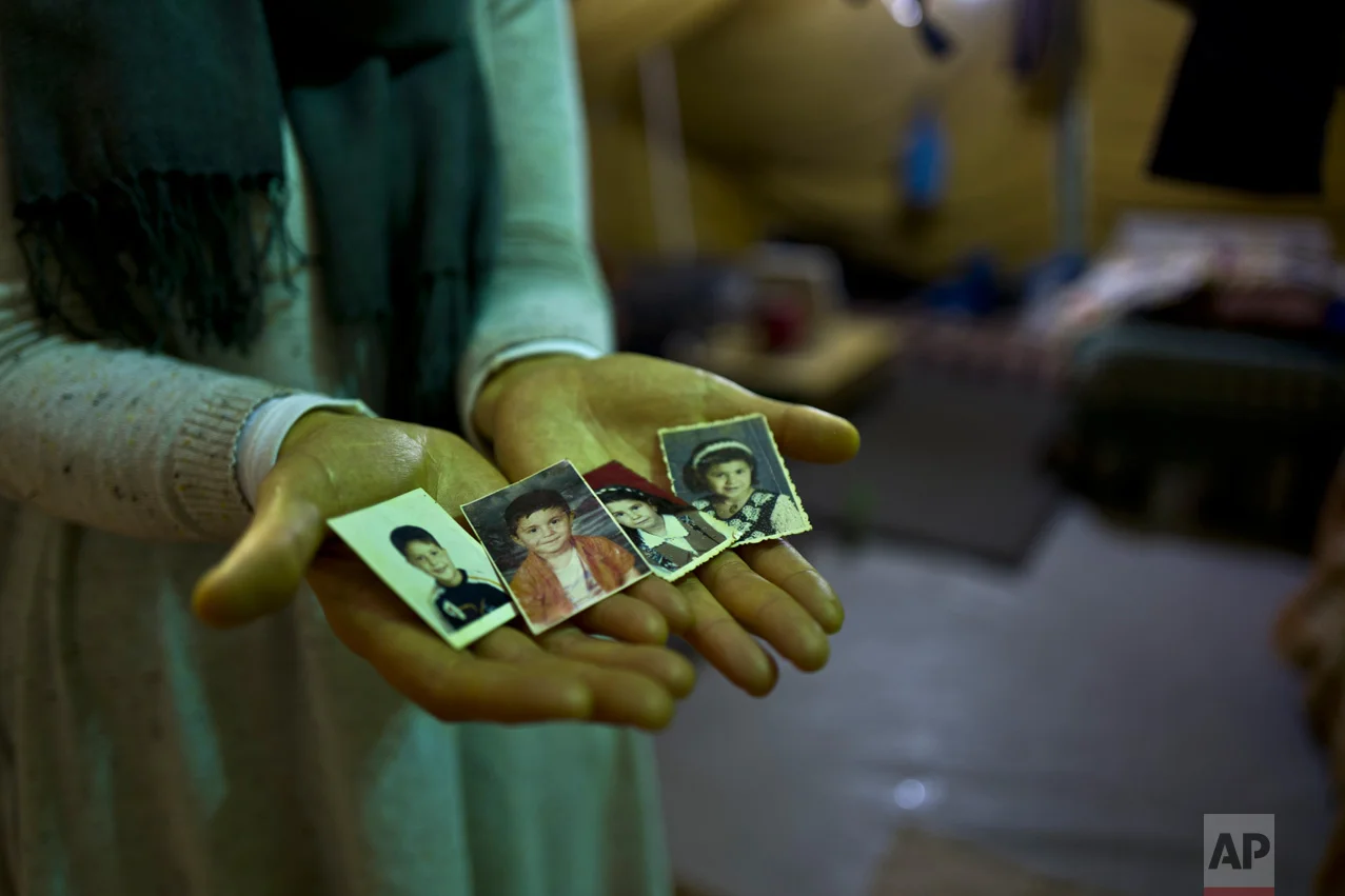 In this Tuesday, Jan. 17, 2017 photo, Sahar Dargzini, 40, a Syrian refugee from Baghdad street in Damascus, shows photographs of her children when they were young, from right, Amal who currently is 24 and lives in Norway, Dania who currently is 26 and lives in Turkey, Mohyeddin, who currently is 15 and lives in Sweden and Salahudin who currently is 20 and lives in Sweden, at her tent in Kalochori refugee camp on the outskirts of the northern Greek city of Thessaloniki. "I love keeping my children pictures with me all the times, they will always remain my children, I hope they will allow me to go to Norway and be with my daughter and see my granddaughter Mirna." Sahar said. (AP Photo/Muhammed Muheisen)