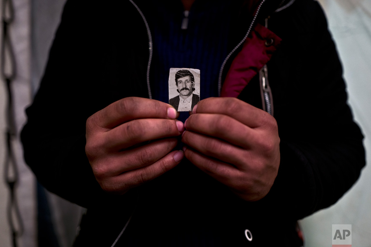 In this Wednesday, Jan. 18, 2017 photo, Dilgash Hassan, 31, a Syrian refugee from al-Hasaka, holds a photograph of his father Khalil when he was younger, at Frakapor refugee camp on the outskirts of the northern Greek city of Thessaloniki. "I have been carrying this picture for the last ten years, it is a holy picture for me, my father is my role model." Dilgash said. (AP Photo/Muhammed Muheisen)
