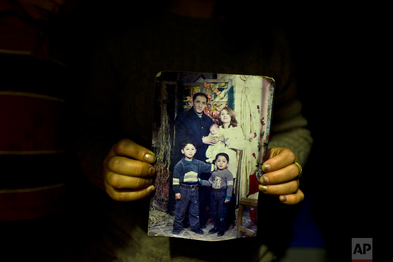 In this Thursday, Jan. 19, 2017 photo, Fidan Kiru, 31, a Syrian refugee from Afrin, holds a photograph taken in 2004 showing herself and her husband Mohyeddin, when he was 27-years-old, and her sons, younger to older, Avindar, 8 months, Khalid, 4 and Levant, 6, at her tent in Kalochori refugee camp on the outskirts of the northern Greek city of Thessaloniki. "This is the only group family picture we have, my husband is currently in Germany and I hope they will allow me to join him." Fidan said. (AP Photo/Muhammed Muheisen)
