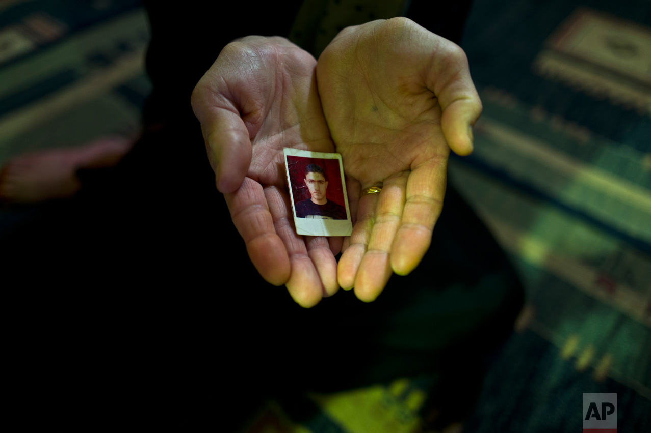 In this Tuesday, Jan. 17, 2017 photo, Suad Abdulmajeed, 57, a Syrian refugee from Al-Qamishly, shows a photograph of her son Ayaz, at her tent in Kalochori refugee camp on the outskirts of the northern Greek city of Thessaloniki. "We fled from Bashar, referring to the Syrian president, and the Islamic State with nothing but fear, we just wanted to be safe, my son and husband are in Germany, and all I want is to be with them." Suad said. (AP Photo/Muhammed Muheisen)