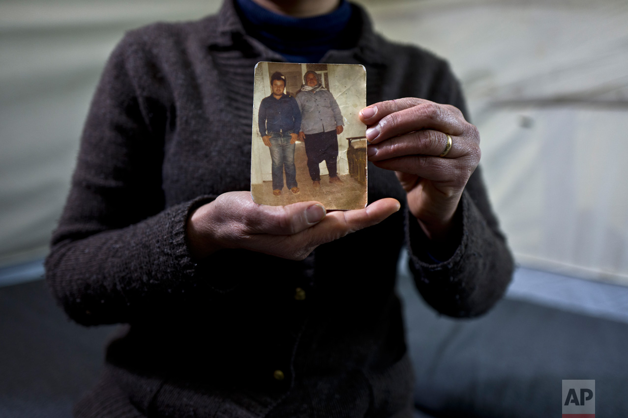 In this Wednesday, Jan. 18, 2017 photo, Habeeba Waqas, 40, a Syrian refugee from Aleppo, holds a photograph showing her husband Mohammed and her father in law Suliman at her tent in Frakapor refugee camp on the outskirts of the northern Greek city of Thessaloniki. "This is the only memory that I carried with me from Syria, my husband was young and handsome in this picture." Habeeba said. (AP Photo/Muhammed Muheisen)