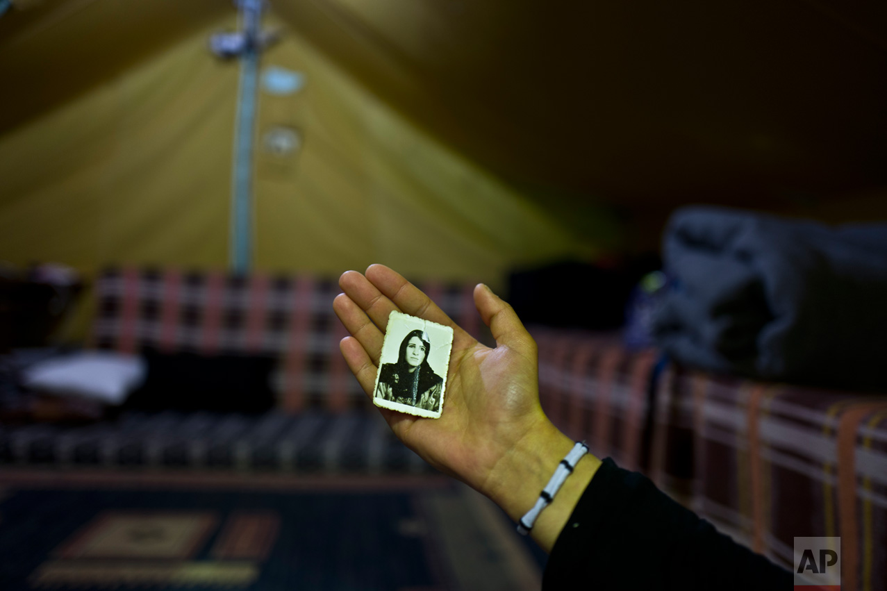 In this Tuesday, Jan. 17, 2017 photo, Kulnawaz Youssef, 13, a Syrian refugee from Al-Qamishly, shows a photograph of her mother Suad, at her tent in Kalochori refugee camp on the outskirts of the northern Greek city of Thessaloniki. "We fled our home with nothing, having my mother's photograph with me makes me feel safe." Kulnawaz said. (AP Photo/Muhammed Muheisen)