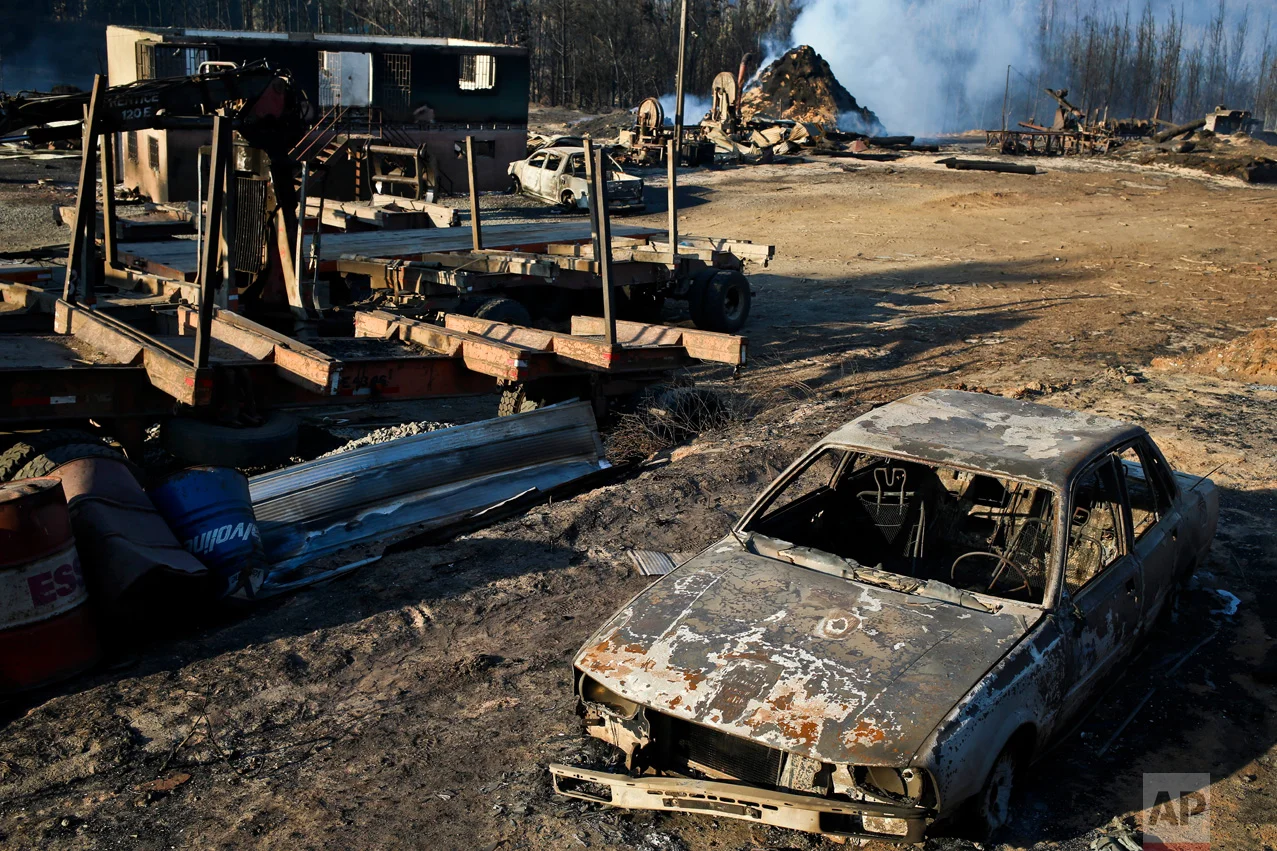 Scorched trees, vehicles and debris cover the landscape of a sawmill consumed by wildfires in the community Santa Olga, Chile, Tuesday, Jan. 31, 2017. The fires have been raging in central and southern Chile, fanned by strong winds, hot temperatures and a prolonged drought. (AP Photo/Esteban Felix)