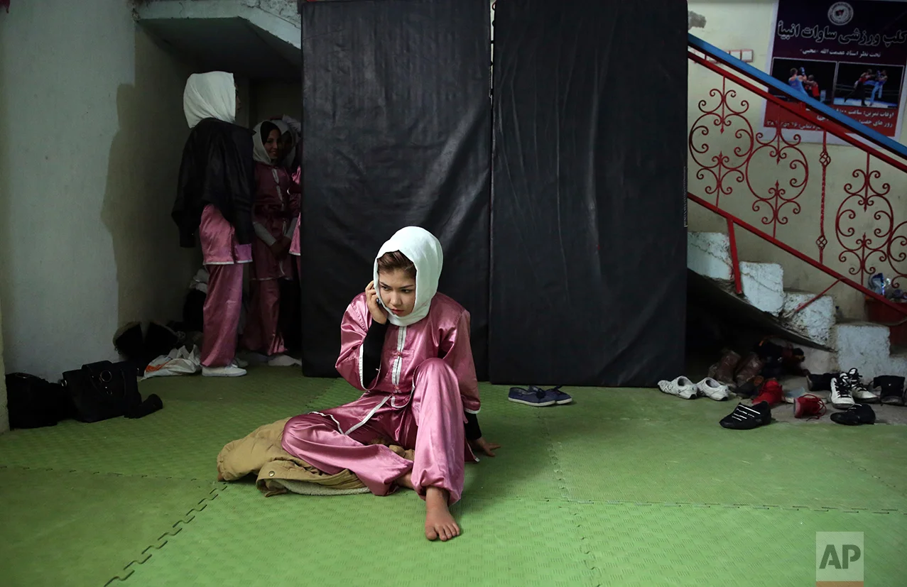 A Shaolin martial arts student talks on her phone, during a pause in a training session at their club in Kabul, Afghanistan, Tuesday, Jan. 25, 2017. When they aren’t training on the snow covered hills that surround Kabul, the students train in a grungy, dark club financed by a young cinema actor. (AP Photos/Massoud Hossaini)