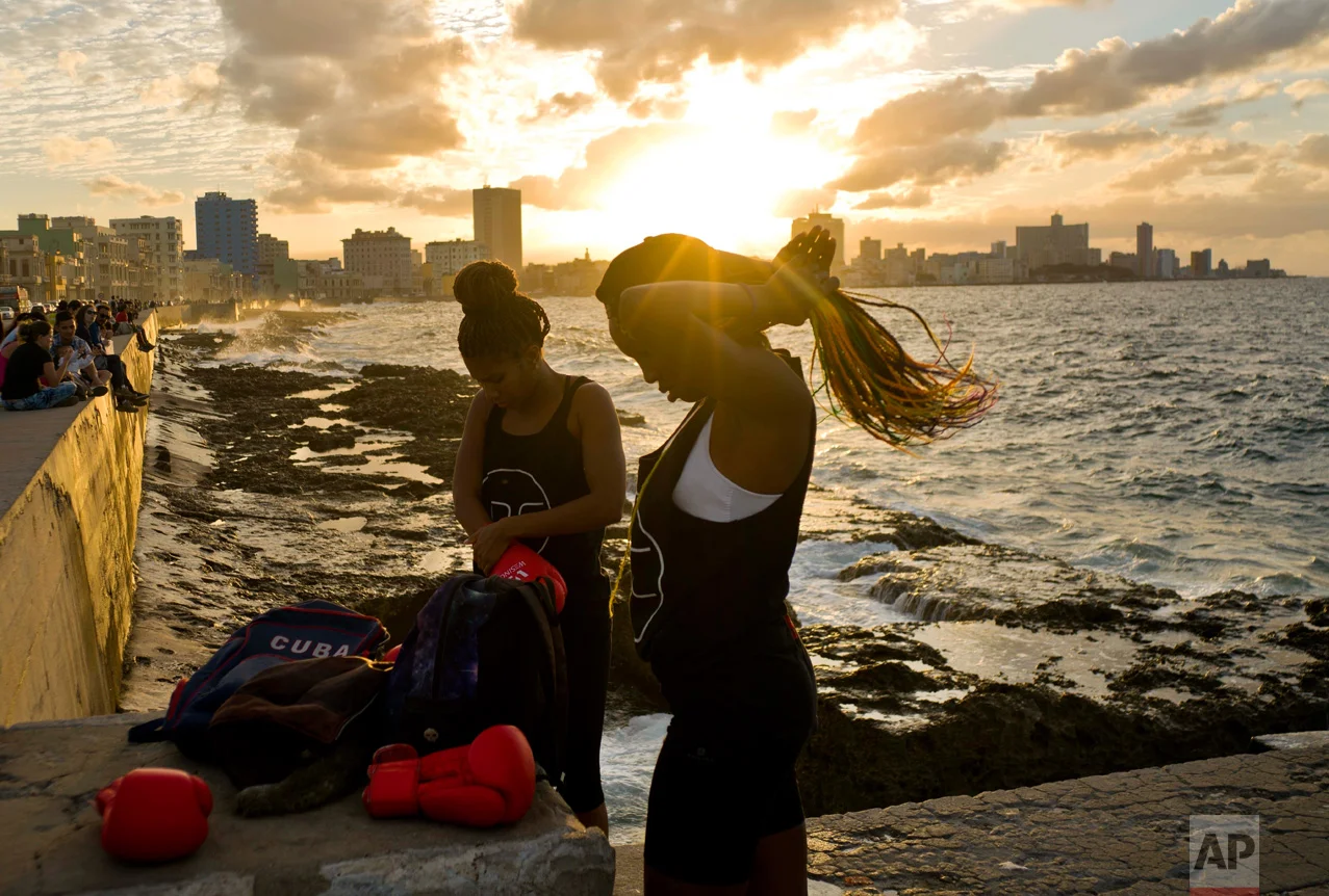 In this Jan. 30, 2017 photo, boxers Idamelys Moreno, left, and Legnis Cala, get ready for a photo session on Havana's Malecon, in Cuba. Moreno trains at least two hours a day after she gets off work, completing a routine that includes running several miles, lifting weights, hitting a punching bag and sparring with both women and men. (AP Photo/Ramon Espinosa)