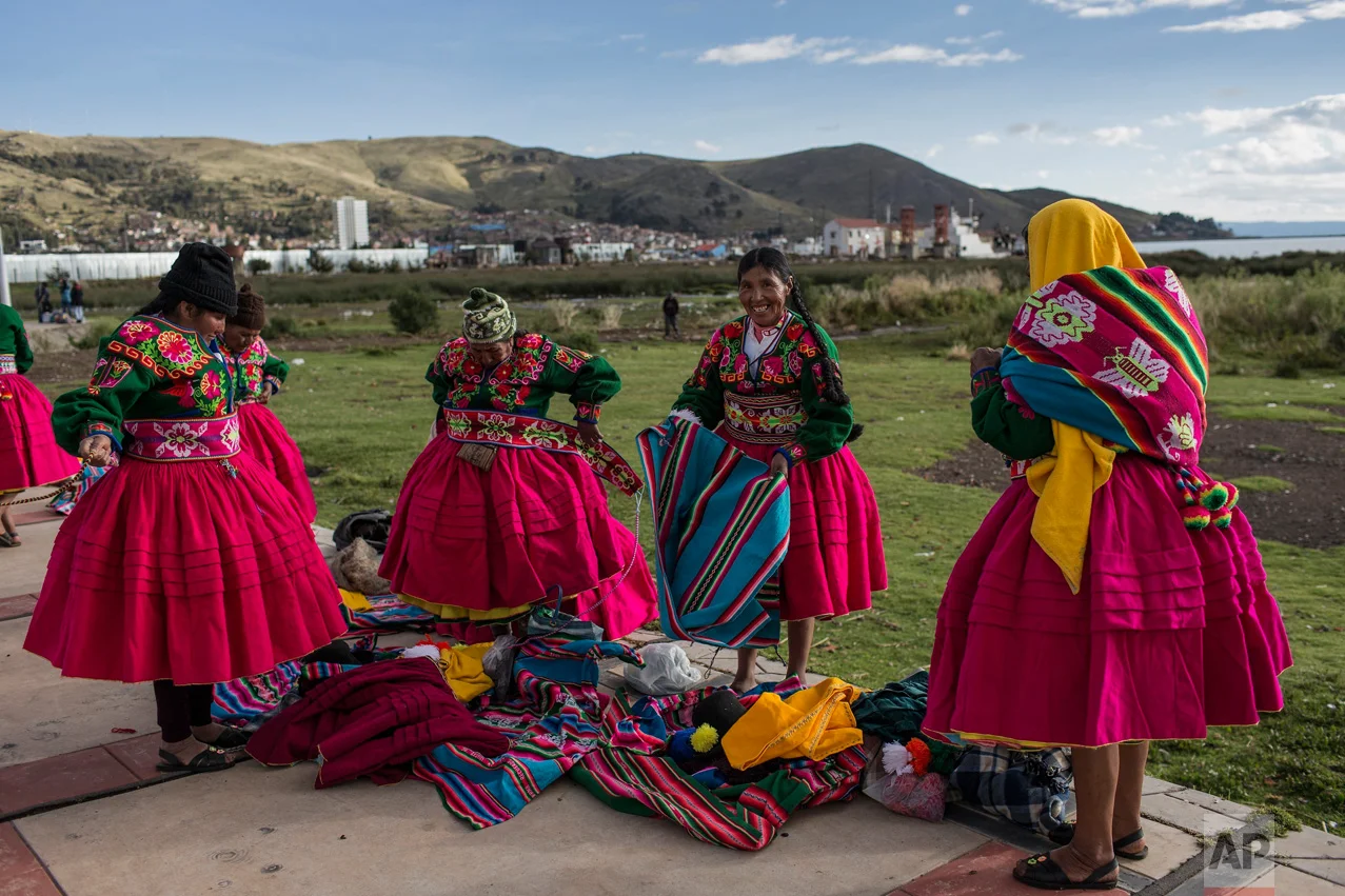 In this Jan. 29, 2017 photo, dancers put on their costumes near the shore of Lake Titicaca prior to their performance for Virgin of Candelaria celebrations in Puno, Peru. Some competing groups wear shoes made with alpaca skin, collars hung with ears…