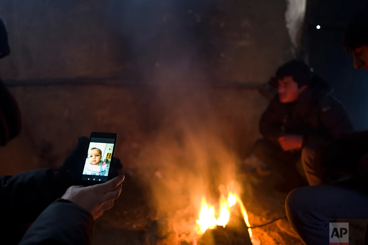 Refugee Ayoub Ahmadzai, 35, from Kandahar, Afghanistan looks at a picture of his daughter Tamana on his mobile phone, while he and others took refuge in an abandoned warehouse in Belgrade, Serbia, Saturday, Jan. 28, 2017. (AP Photo/Muhammed Muheisen)