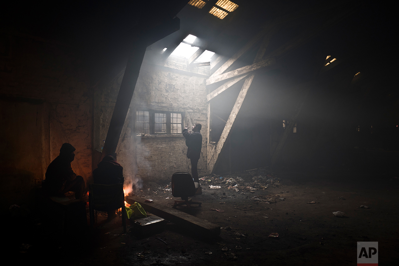  An Afghan refugee man, center, shaves his beard while others warm themselves around a fire, in an abandoned warehouse in Belgrade, Serbia, Sunday, Jan. 29, 2017. (AP Photo/Muhammed Muheisen) 