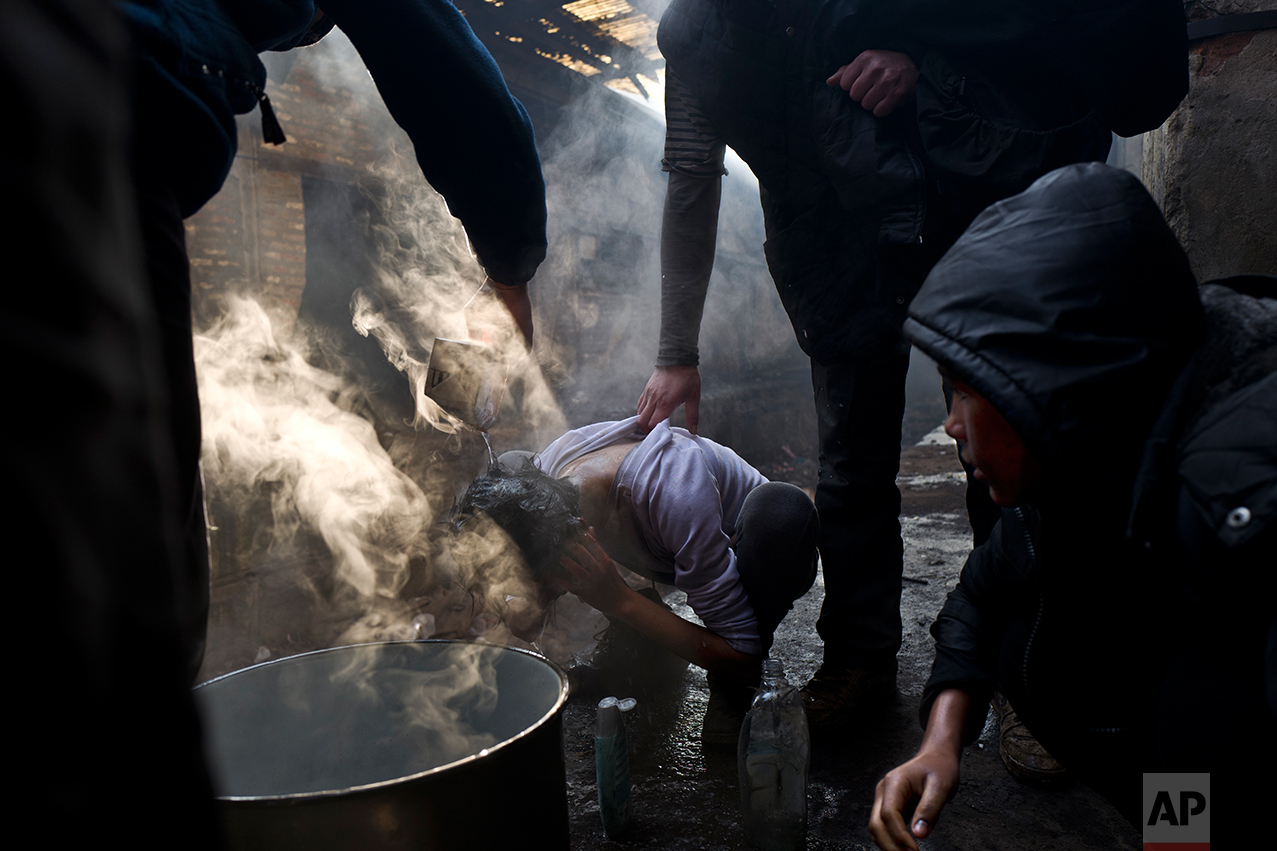  A migrant is helped by others to wash his hair in an abandoned warehouse in Belgrade, Serbia, Monday, Jan. 30, 2017. (AP Photo/Muhammed Muheisen) 