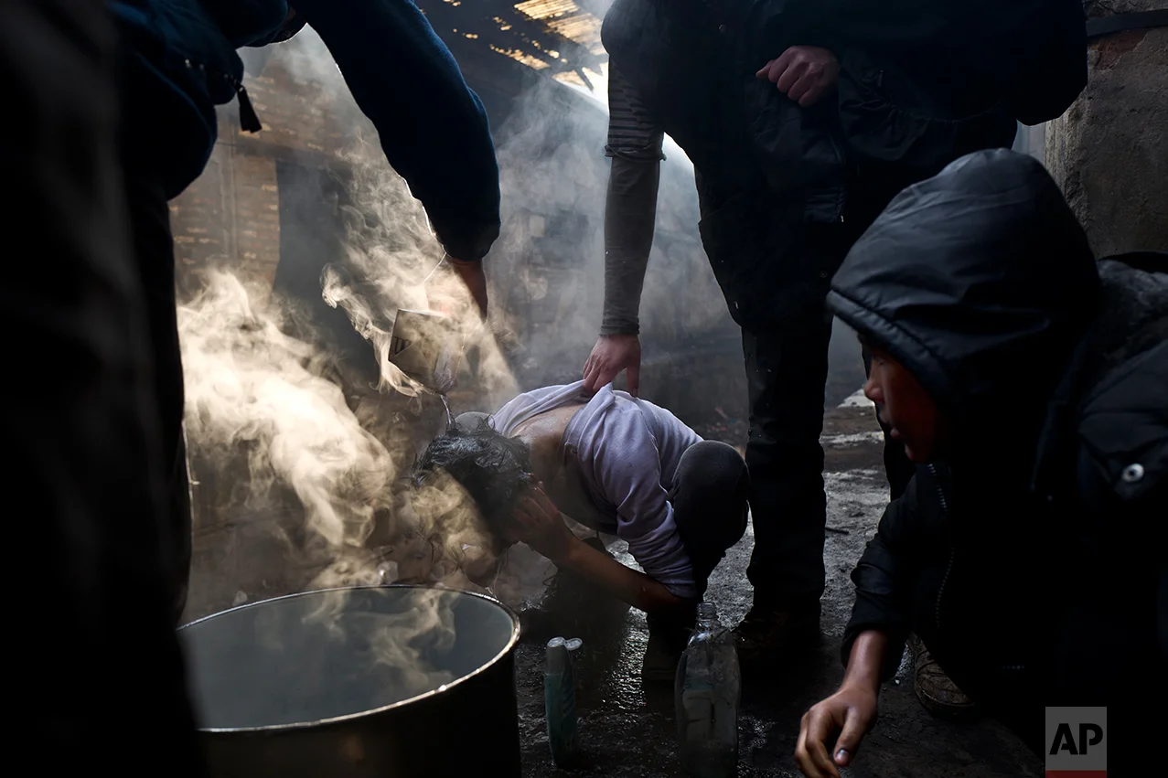 A migrant is helped by others to wash his hair in an abandoned warehouse in Belgrade, Serbia, Monday, Jan. 30, 2017. (AP Photo/Muhammed Muheisen)