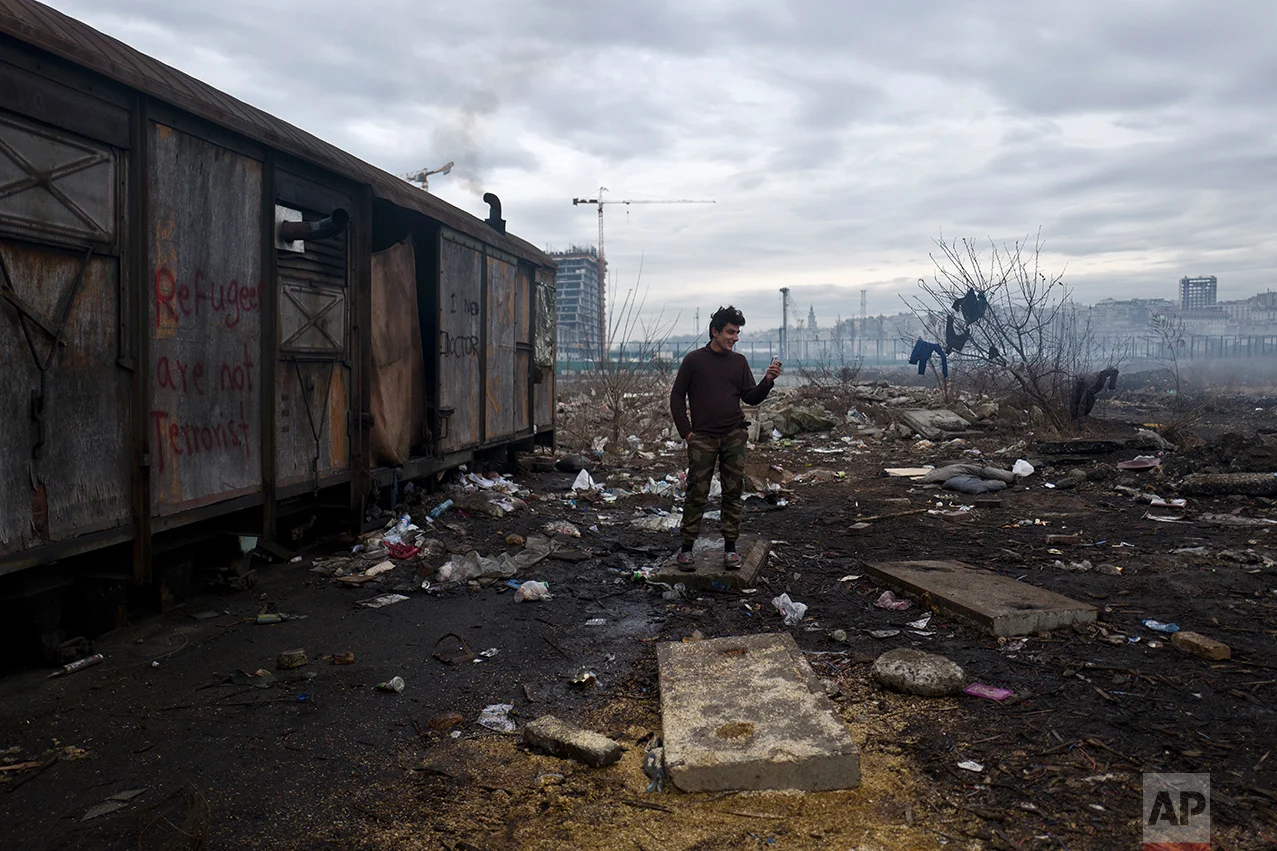 An Afghan refugee speaks on a mobile phone outside an old train carriage where he and other migrants took refuge in Belgrade, Serbia, Thursday, Feb. 2, 2017. (AP Photo/Muhammed Muheisen)