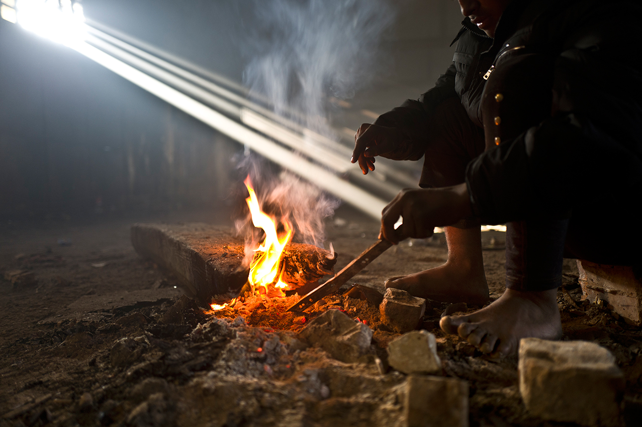 An Afghan refugee youth warms his legs and hands around a fire in an abandoned warehouse in Belgrade, Serbia, Monday, Jan. 30, 2017. (AP Photo/Muhammed Muheisen)