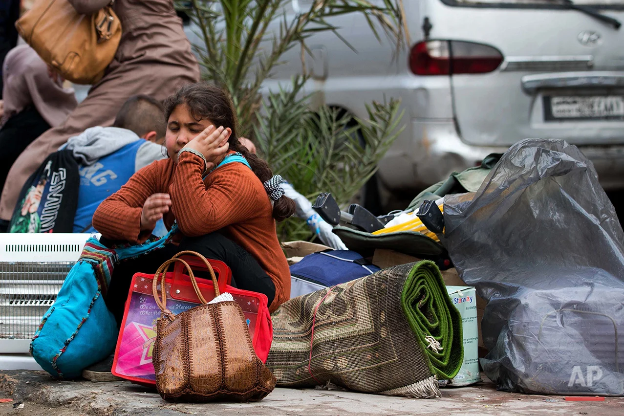 In this picture taken Thursday, April 14, 2016, a Syrian girl waits for her family to load their belongings onto a bus in the town of Palmyra in the central Homs province, Syria. Thousands of residents of this ancient town who fled Islamic State rule are returning briefly to check on their homes and salvage what they can _ some carpets, blankets, a fridge or a few family mementos. (AP Photo/Hassan Ammar)