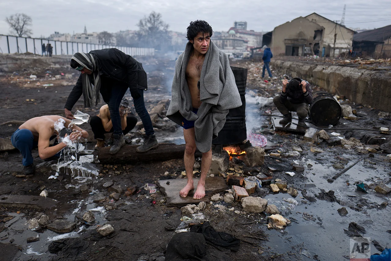 Afghan refugee men shower outside an abandoned warehouse where they are taking refuge in Belgrade, Serbia, Thursday, Feb. 2, 2017. (AP Photo/Muhammed Muheisen)