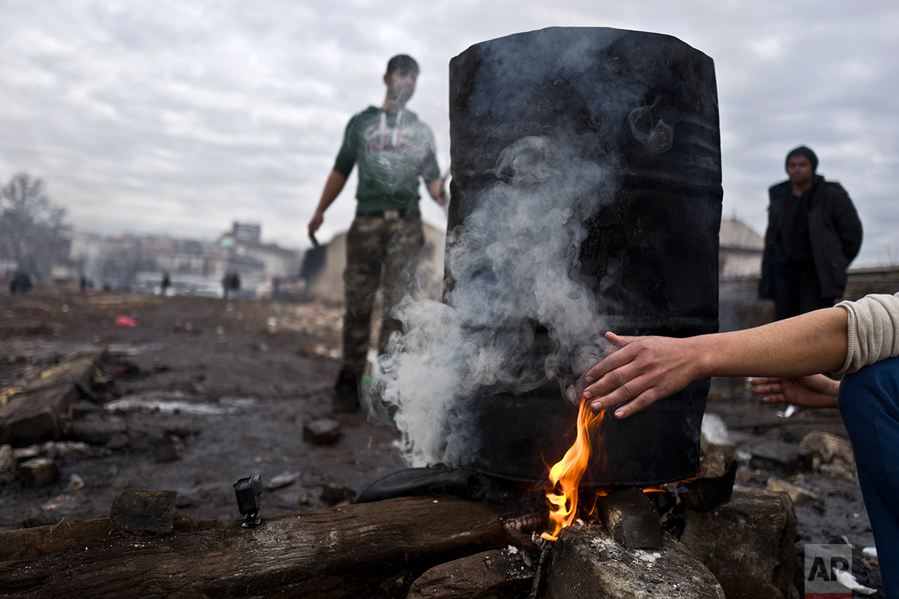  An Afghan refugee youth warms his hand while waiting for the water to boil and have a shower outside an abandoned warehouse where he and other migrants are taking refuge in Belgrade, Serbia, Thursday, Feb. 2, 2017. (AP Photo/Muhammed Muheisen) 