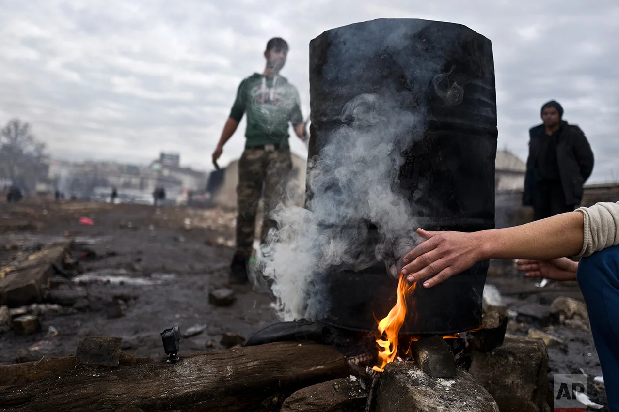 An Afghan refugee youth warms his hand while waiting for the water to boil and have a shower outside an abandoned warehouse where he and other migrants are taking refuge in Belgrade, Serbia, Thursday, Feb. 2, 2017. (AP Photo/Muhammed Muheisen)