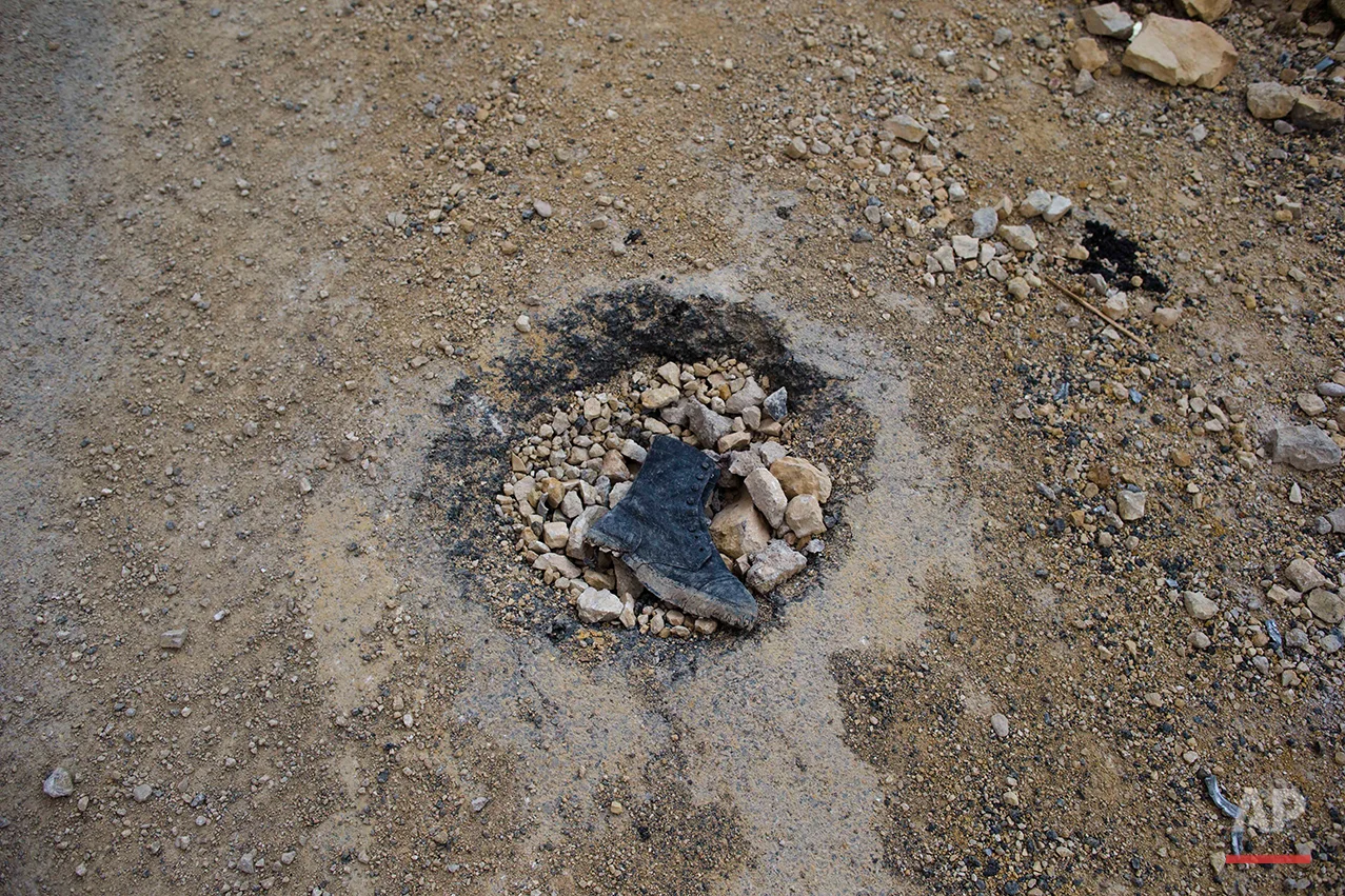 An army boot, thought to be belonging to an Islamic State fighter left in a hole outside of the Palmyra citadel in the central Homs province, Syria, Thursday, April 14, 2016. Russian combat engineers arrived in Syria on a mission to clear mines in Palmyra, which has been recaptured from Islamic State militants in an offensive that has proven Russia’s military might in Syria despite a drawdown of its warplanes. (AP Photo/Hassan Ammar)