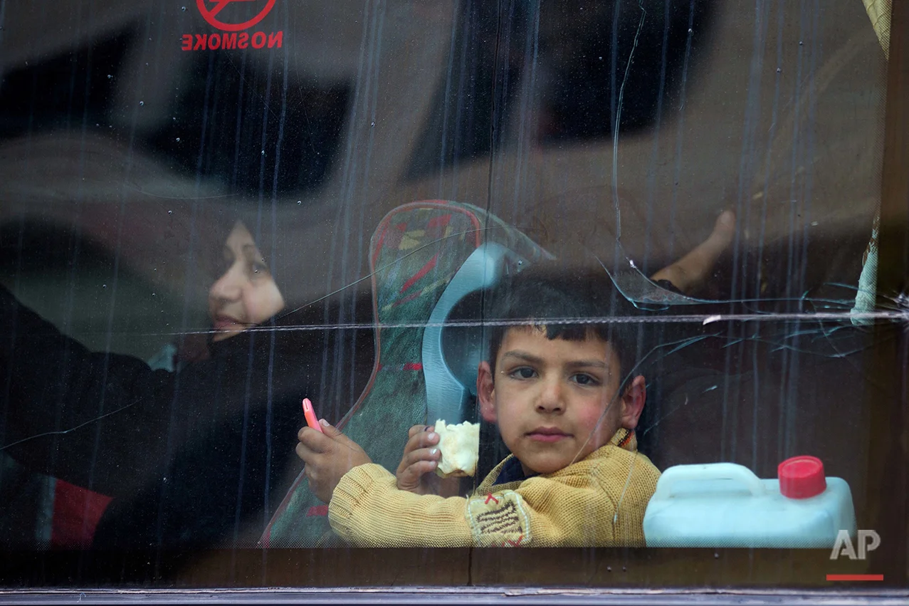 In this picture taken Thursday, April 14, 2016, a Syrian child looks through a window after his family loaded their belongings onto a bus in the town of Palmyra in the central Homs province, Syria. (AP Photo/Hassan Ammar)