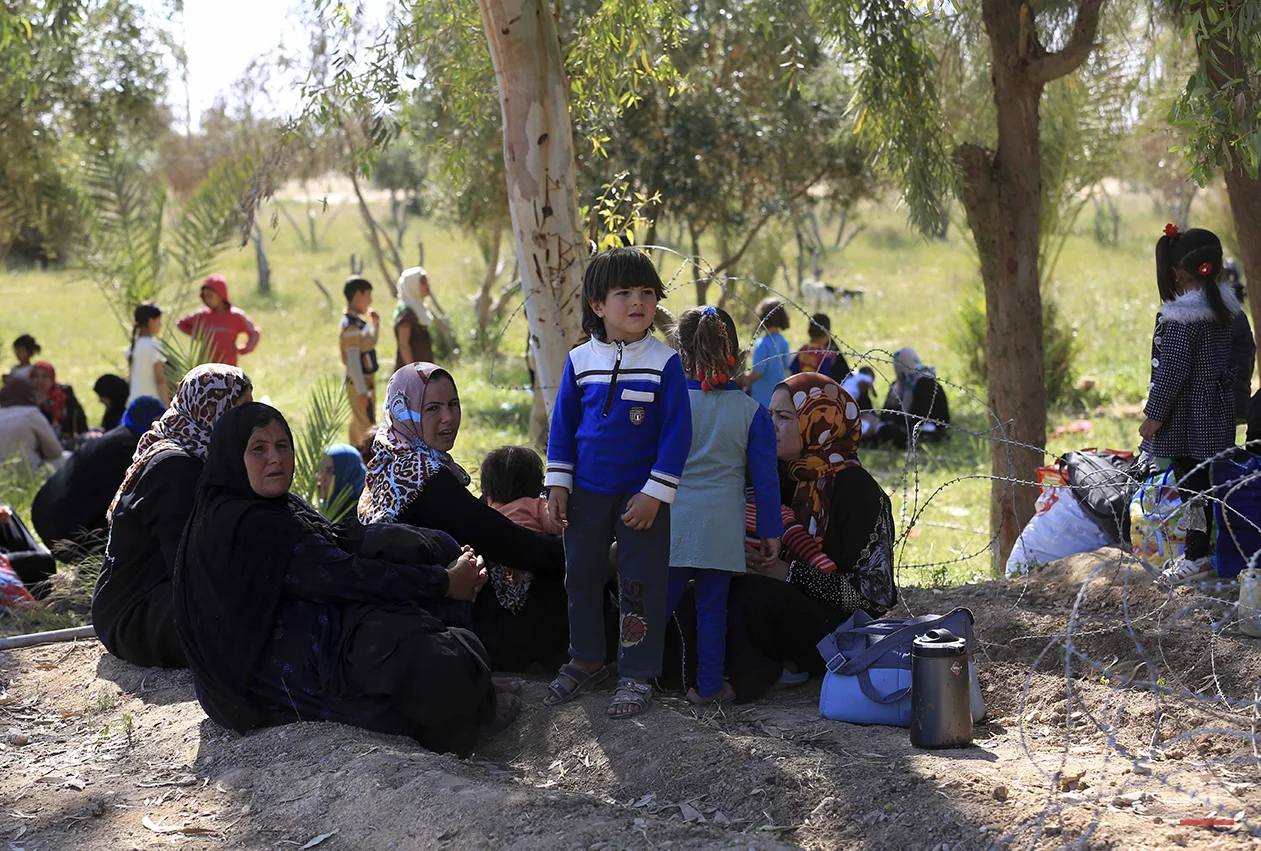 People rest as they flee their homes during clashes between Iraqi security forces and Islamic State group in Hit, 85 miles (140 kilometers) west of Baghdad, Iraq, Monday, April 4, 2016. Families, many with small children and elderly relatives say they walked for hours Monday through desert littered with roadside bombs to escape airstrikes and clashes. (AP Photo/Khalid Mohammed)