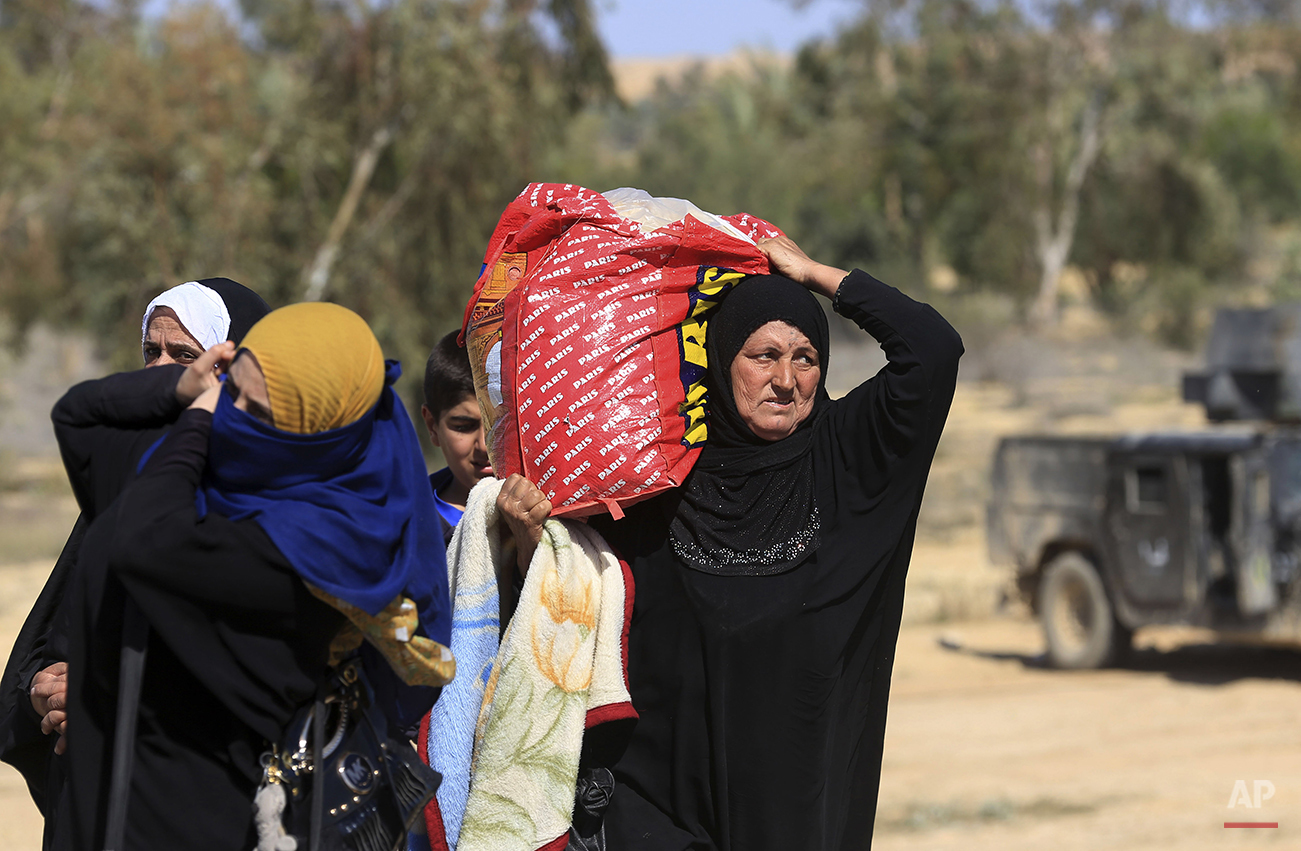 Iraqi women flee their homes during clashes between Iraqi security forces and Islamic State group in Hit, 85 miles (140 kilometers) west of Baghdad, Iraq, Monday, April 4, 2016. Families, many with small children and elderly relatives say they walked for hours Monday through desert littered with roadside bombs to escape airstrikes and clashes. (AP Photo/Khalid Mohammed)