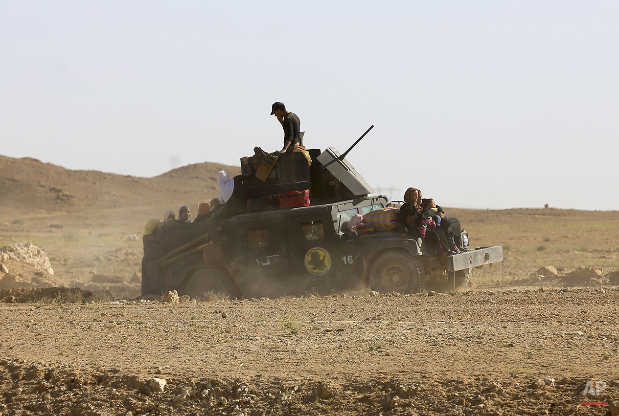 Elite counter terrorism forces transport women and children fleeing their homes during clashes between Iraqi security forces and Islamic State group in Hit, 85 miles (140 kilometers) west of Baghdad, Iraq, Monday, April 4, 2016. Families, many with small children and elderly relatives say they walked for hours Monday through desert littered with roadside bombs to escape airstrikes and clashes. (AP Photo/Khalid Mohammed)