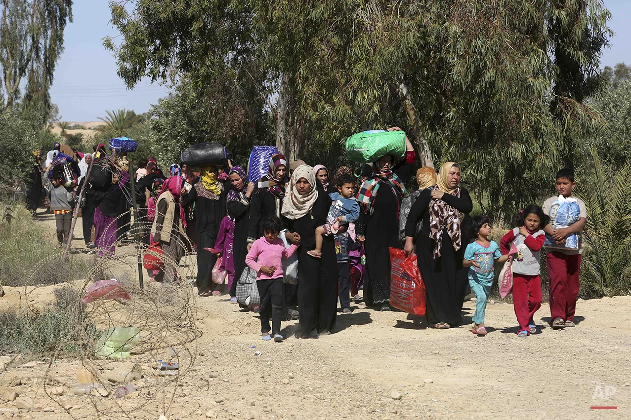 People flee their homes during clashes between Iraqi security forces and Islamic State group in Hit, 85 miles (140 kilometers) west of Baghdad, Iraq, Monday, April 4, 2016. Families, many with small children and elderly relatives say they walked for…