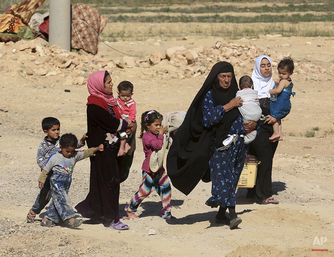 People flee their homes during clashes between Iraqi security forces and Islamic State group in Hit, 85 miles (140 kilometers) west of Baghdad, Iraq, Monday, April 4, 2016. Families, many with small children and elderly relatives say they walked for hours Monday through desert littered with roadside bombs to escape airstrikes and clashes. (AP Photo/Khalid Mohammed)