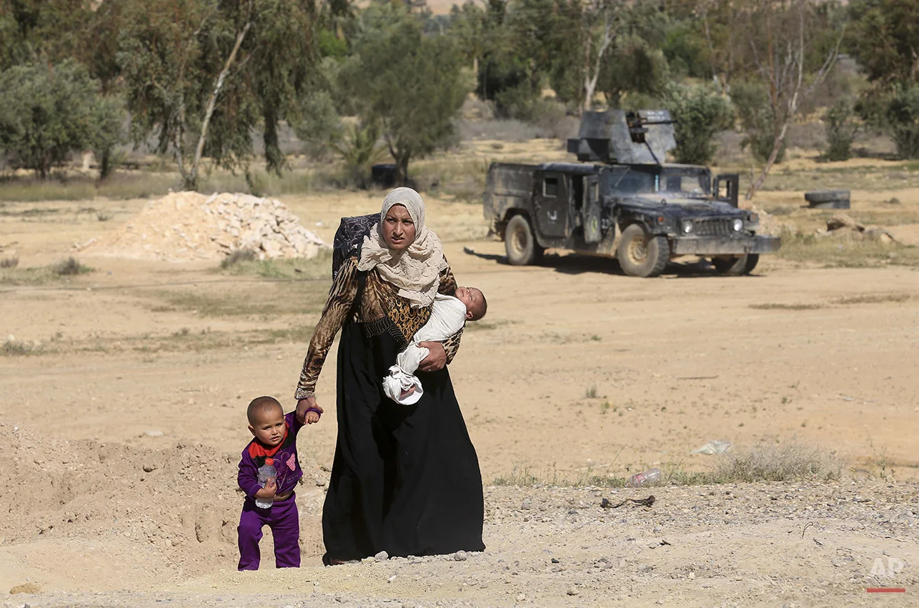 A mother and her children flee their homes during clashes between Iraqi security forces and Islamic State group in Hit, 85 miles (140 kilometers) west of Baghdad, Iraq, Monday, April 4, 2016. Families, many with small children and elderly relatives …
