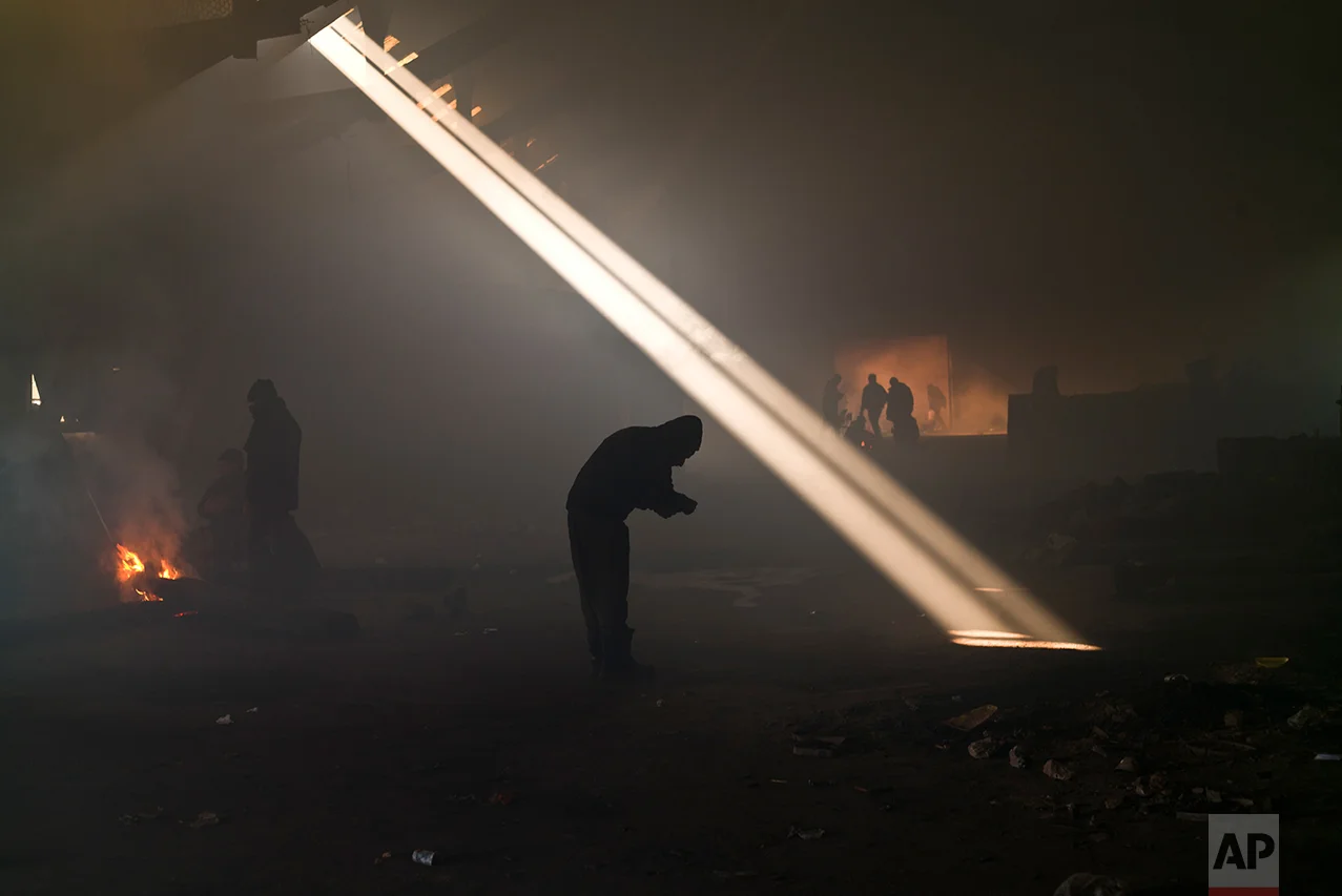 A group of migrants, left, gather around a fire to warm themselves in an abandoned warehouse in Belgrade, Serbia, Monday, Jan. 30, 2017. (AP Photo/Muhammed Muheisen)